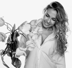 Beautiful curly girl with spring flowers tulips on a white background. black and white