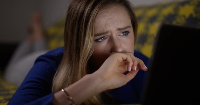 4K Young woman at home surfing the web at night, upset by something she sees on the screen