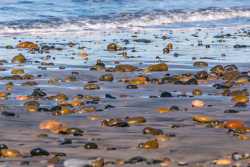 Scattered colorful stones cover the beach at South Carlsbad State Beach in San Diego, California.