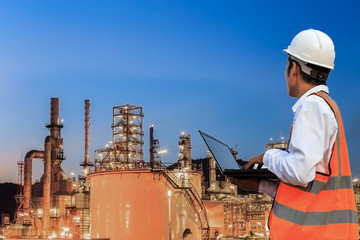 Engineer is checking oil refinery plant with laptop