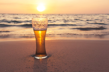 Glass of cold beer on the sea shore at the sunset. Relax on the beach.
