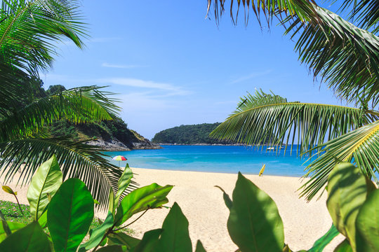 Picturesque view of Andaman sea in Phuket island, Thailand. Seascape with white sand, cliff, palm trees and blue sky. Tropical beach at the exotic island.