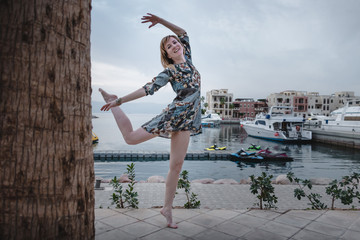 Slender girl has fun near the marina full of yachts in a summer