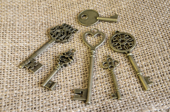 Six antiquarian bronze keys on burlap. Decor. Vintage. Indoors. Horizontal format. Color. Photo.