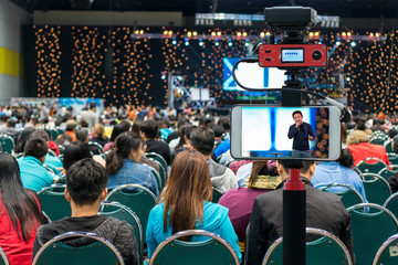 Closeup smart mobile phone taking Live of asian Businessman giving the knowledge on the tage over...