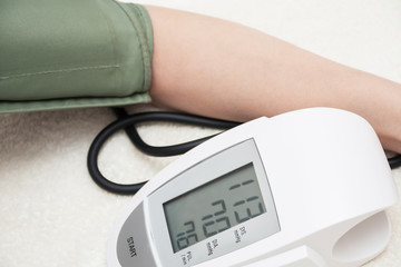 Female is taking care for health and measures her blood pressure with automatic digital blood pressure meter. Closeup, selective focus