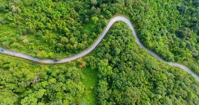 Aerial view of road on mountains and forest with truck driving up hill. Beautiful nature and transportation from panoramic view.
