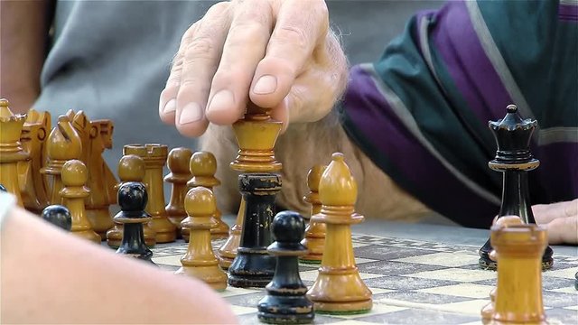 Active retired people, old friends and free time, two seniors having fun and playing chess game at park. 