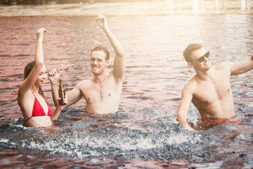 Fototapeta premium Group of friends enjoying vacation in summer time. Young people having fun dancing in swimming pool