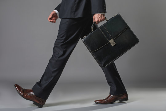 Low angle close up of male legs. Man walking in business suit with suitcase