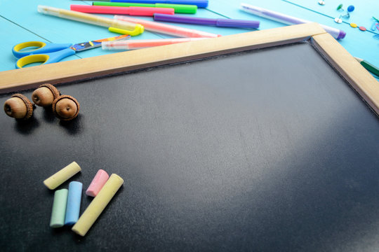 
The frame of school supplies (pencils, paints, paper, brushes, markers) on a blackboard. 