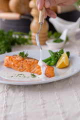 Salmon steak with white sauce on a white plate in the dining room