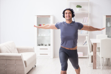 Fototapeta na wymiar Man doing sports at home and listening to music