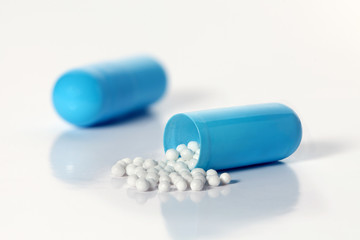 Opened blue capsule with medicine on a gray background