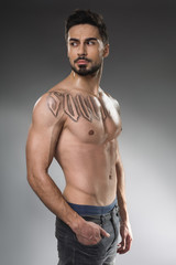 Fototapeta premium Sport concept. Portrait of thoughtful sportsman with athletic figure standing with nude torso. Isolated on background