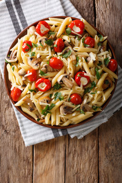 Penne pasta with fried mushrooms, tomatoes, pepper and cheese close-up. Vertical top view