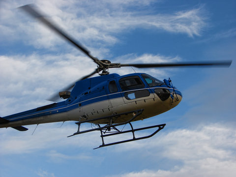 Blue helicopter on sky with clouds