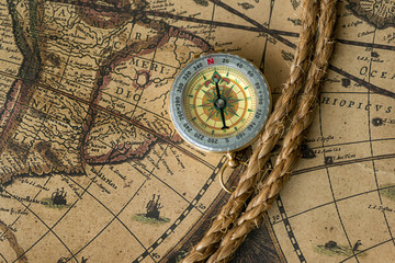 Old compass on vintage map with rope