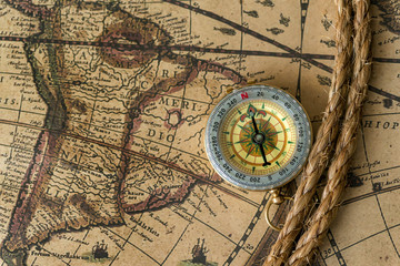 Fototapeta na wymiar Old compass on vintage map with rope