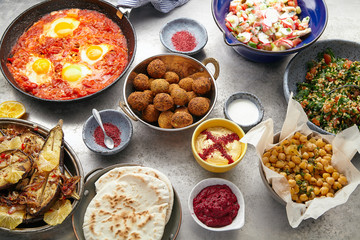 Overhead image of traditional jewish and middle eastern food: falafel, fattoush, tabouli, shakshuka, balila, hummus, roasted eggplants and spicy beetroot dip. Israeli cuisine concept