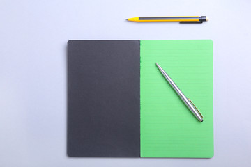 Modern white office desk table with laptop, smartphone and other supplies. Blank notebook page for input the text in the middle. Top view.