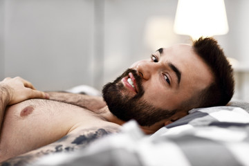 Happy man lying in bedroom
