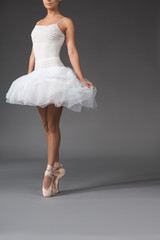 Gracefulness concept. Slim woman in tutu rising at the tips of her fingers. Copy space in right side