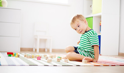 two years old child sitting on the floor with wooden cubes