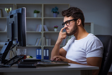 Young man staying late in office to do overtime work