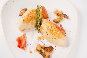 Traditional polish dish called kartacz - potato dumplings stuffed with meat and served with crispy bacon, caramelized onion and fried boletus