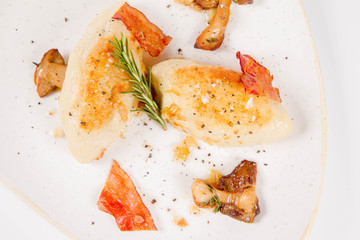 Traditional polish dish called kartacz - potato dumplings stuffed with meat and served with crispy bacon, caramelized onion and fried boletus