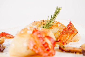 Traditional polish dish called kartacz - potato dumplings stuffed with meat and served with crispy bacon, caramelized onion and fried boletus