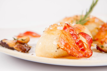 Traditional polish dish called kartacz - potato dumplings stuffed with meat and served with crispy bacon, caramelized onion and fried boletus