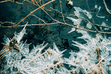 Ice fragments under thin layer of frozen river water. Dark blue natural background