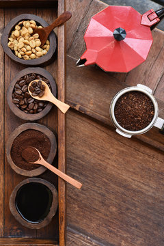 Freshly ground coffee beans in a metal filter and coffee beans in bowl with red kettle on the side.