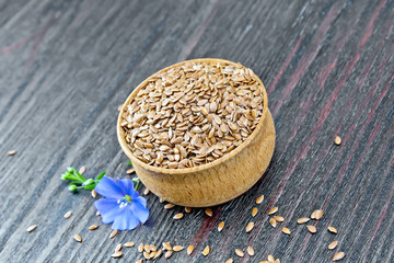 Flaxen brown seed in bowl with flower on board