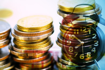 Double exposure of coin stack and alarm clock with city background and financial graph, business finance concept.