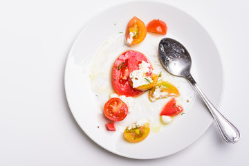 Tomato salad with fresh cheese, olive oil and black pepper on white plate background