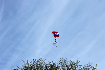 the paratrooper flies in the sky above the ground, freedom of flight