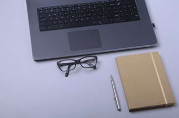 Close-up of comfortable working place in office with laptop, notebook, glasses, pen and other equipment laying on table with copy space.