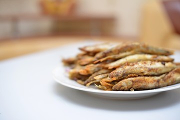 Fried smelt in a frying pan on the table with spices, lime and thyme. Small crispy fish. Selective focus