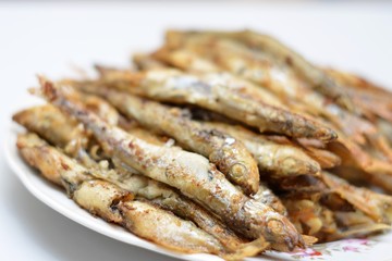 Fried smelt in a frying pan on the table with spices, lime and thyme. Small crispy fish. Selective focus