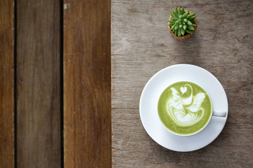 A cup of green tea matcha latte on wooden background