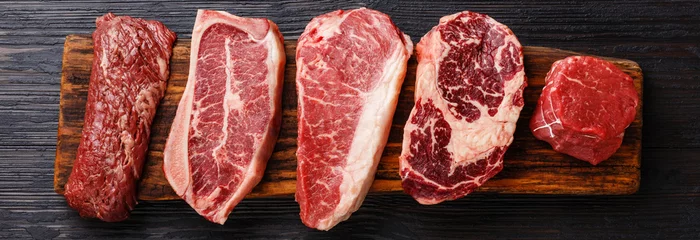Photo sur Plexiglas Viande Variété de steaks de viande crue Black Angus Prime, machette, lame sur os, contre-filet, faux-filet, filet mignon sur planche de bois