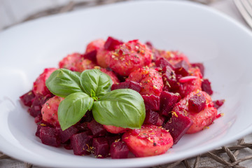 Home-made gnocchi and beet root on white plate