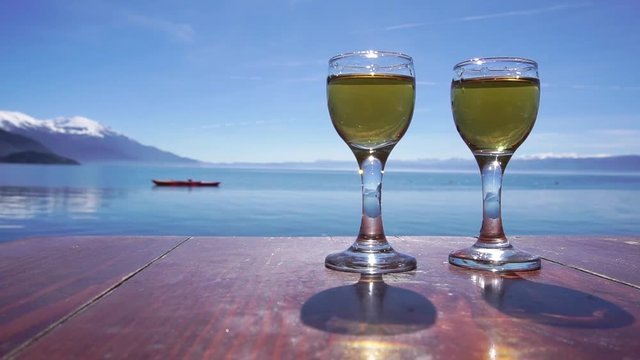 Hand reaching glass of rakija against Ohrid Lake, Macedonia