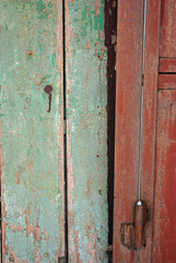 Door frame with shabby green and door with  handle of dark red color, grunge texture background