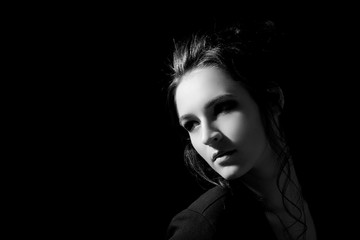Girl in fashion style looks inside a close-up on a black background with space for text