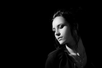 Studio portrait of a girl with evening make-up on closed eyes in fashion style in a low key on a black background with space for text