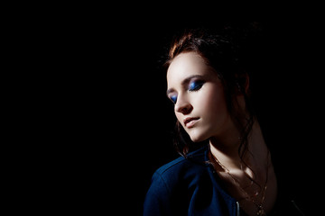Fototapeta premium Studio portrait of a girl with evening make-up on closed eyes in fashion style in a low key on a black background with space for text